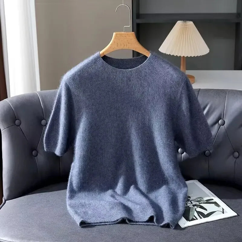 Blue sweater on a hanger against a gray sofa and lamp background