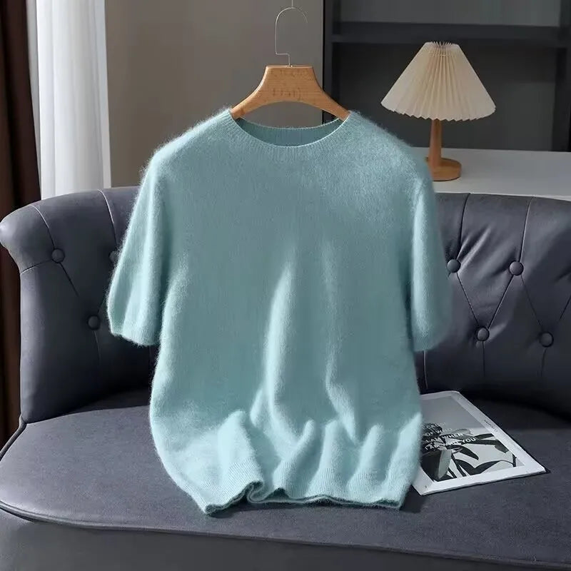 Light blue sweater on a hanger over a gray sofa with a lamp in the background