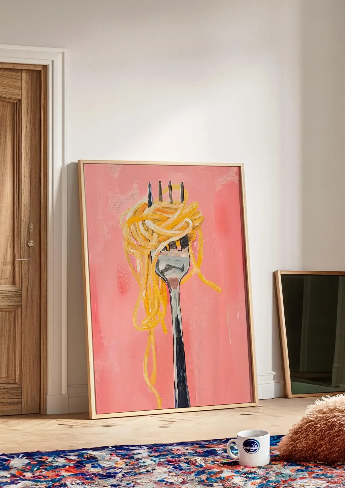Framed artwork of spaghetti on a fork against a pink background in a room with a rug and door.