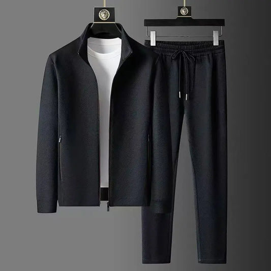 Black jacket and pants set on hangers against a gray background