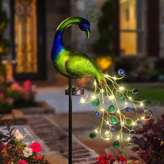 Solar peacock garden light with LED tail lights glowing in outdoor garden setting at night