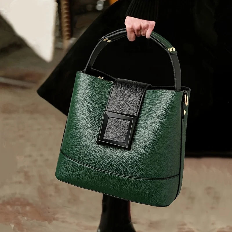 Green handbag with a black handle held by a person.