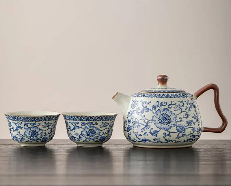 Tea set with teapot and two cups featuring blue floral patterns on a wooden surface.
