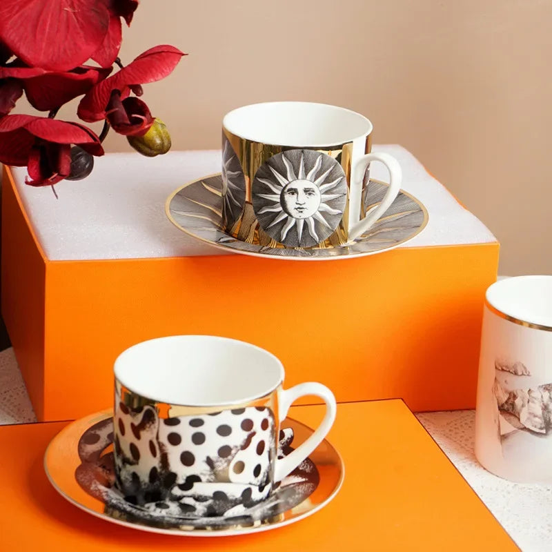 Vintage ceramic cup and matching saucer with artistic black and gold illustration displayed on a modern tabletop.