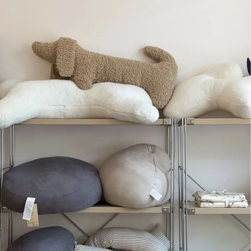 Shelves with various shaped dachshund-shaped cushions in neutral colors against a white wall.