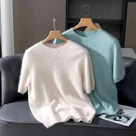 Two sweaters, one white and one light blue, hanging on a chair.