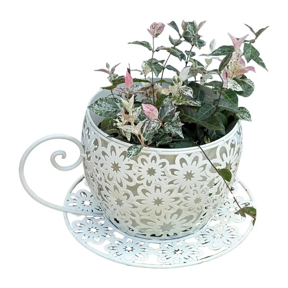 Decorative white teacup planter with a plant on a matching saucer against a white background