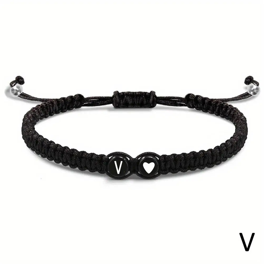 Black braided bracelet with heart and letter 'V' charm on a white background