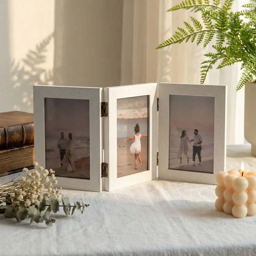 Set of three white photo frames on a surface with scenic images inside, surrounded by decorative items.