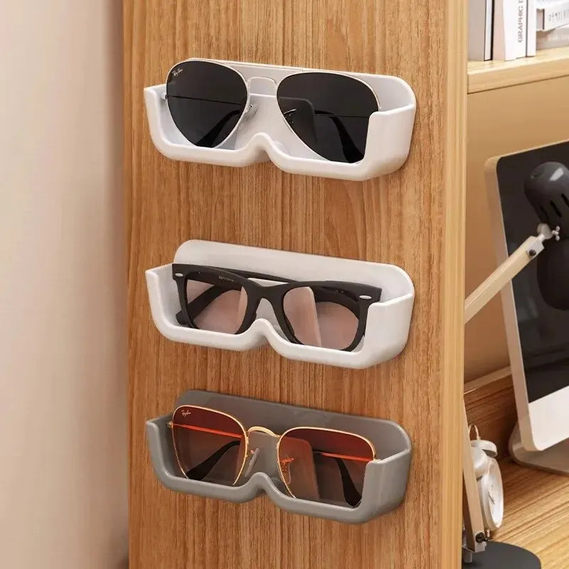 Wall-mounted glasses storage rack holding sunglasses and eyewear in white and grey holders on a wooden surface
