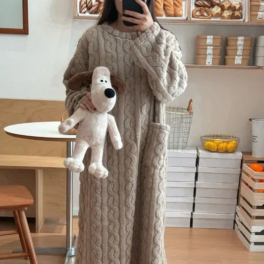 Person wearing a long beige cable knit robe holding a plush dog toy in a cafe setting.