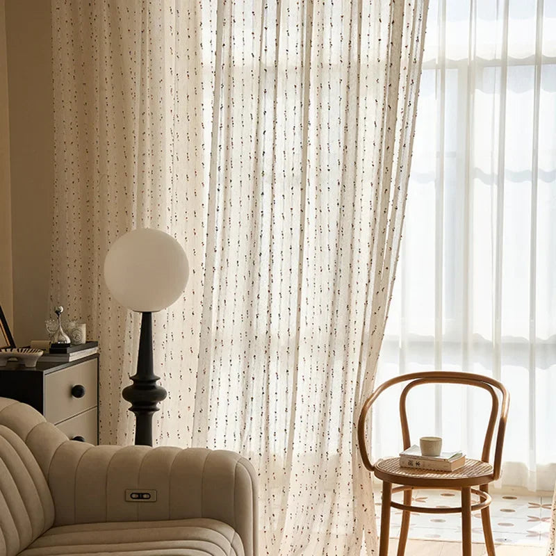 Living room with beige sofa, wooden chair, and sheer curtains.