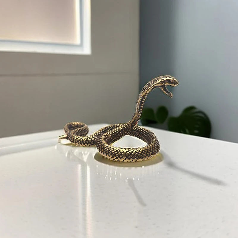 Bronze snake sculpture on a white surface with a neutral background