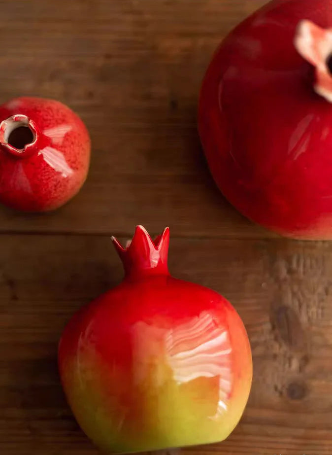 Three pomegranates on a wooden surface with a brand logo in the corner.