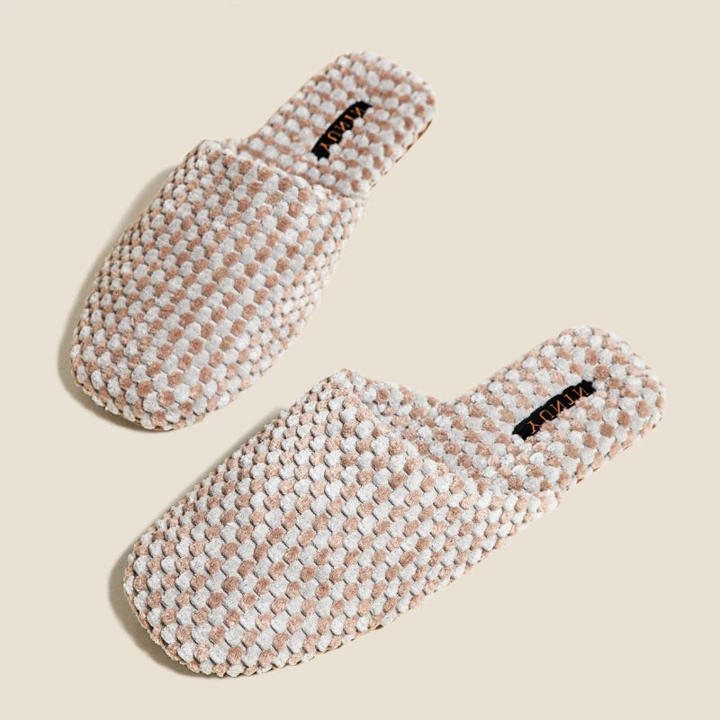 A pair of woven slip-on slippers in a textured cream and light brown pattern, displayed on a solid beige background.
