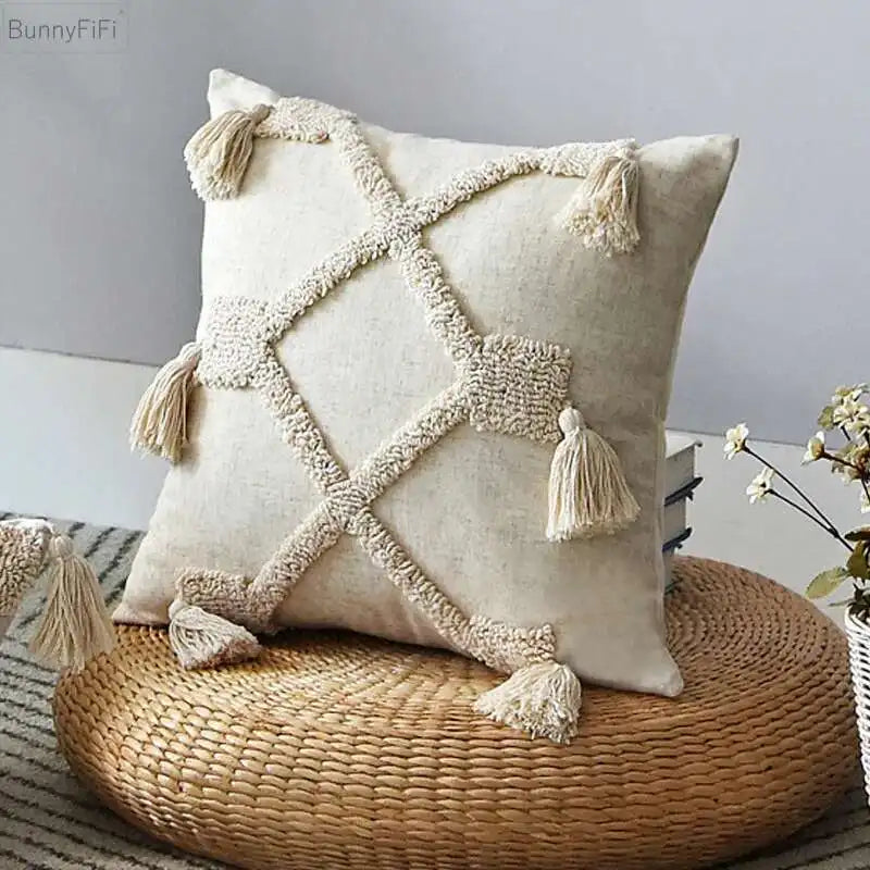 Decorative pillow with tassels on a woven stool against a neutral background