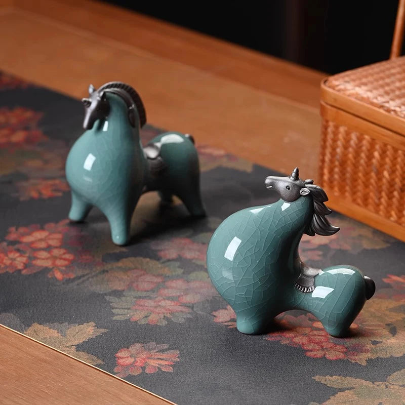 Two green ceramic horse figurines on a floral-patterned surface with a woven basket in the background.