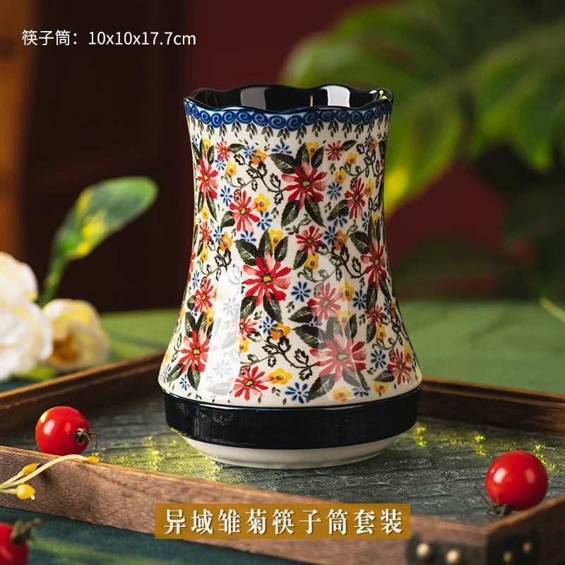 Decorative utensil holder with floral pattern on a wooden tray with greenery