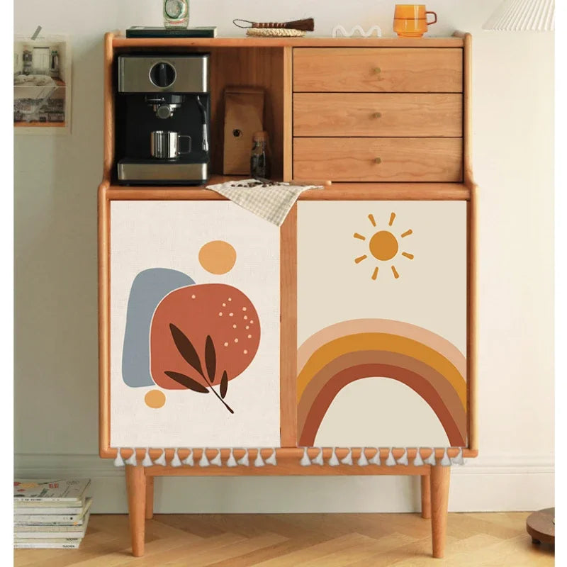 Multiple boho-style self-adhesive cabinet door curtains with abstract sun, moon, rainbow and geometric patterns on wooden cupboards