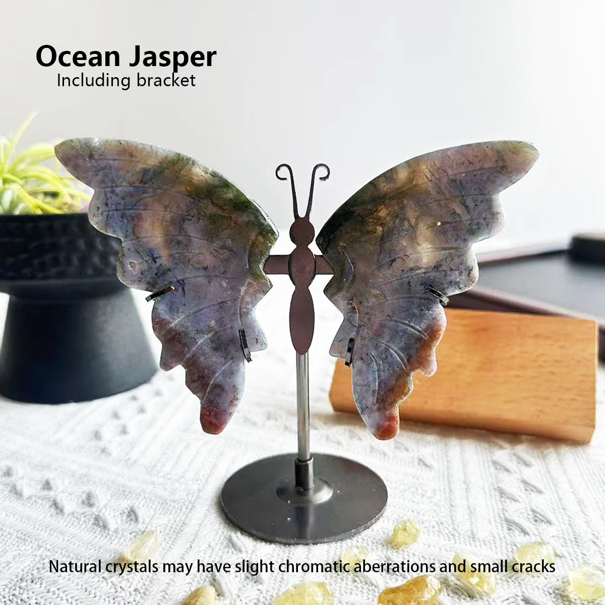 Butterfly-shaped ocean jasper crystal on a stand with a blurred background