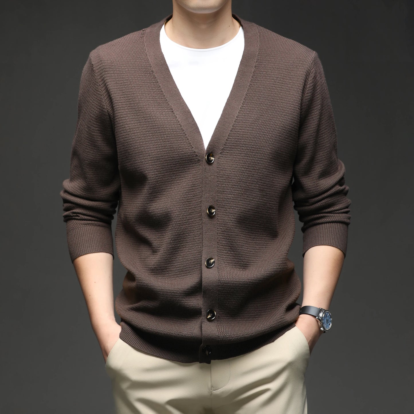 Brown cardigan over a white shirt with beige pants on a dark background