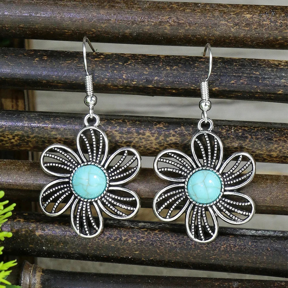 Floral earrings with turquoise centers on a wooden background