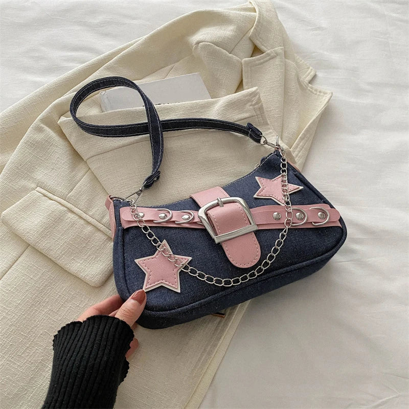 Denim handbag with pink star accents held by a hand on a light-colored fabric background