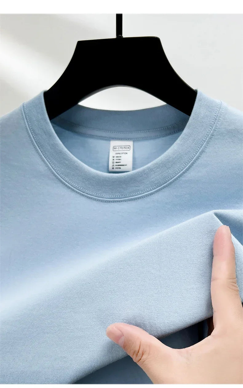 Light blue t-shirt on a hanger with a hand touching the fabric