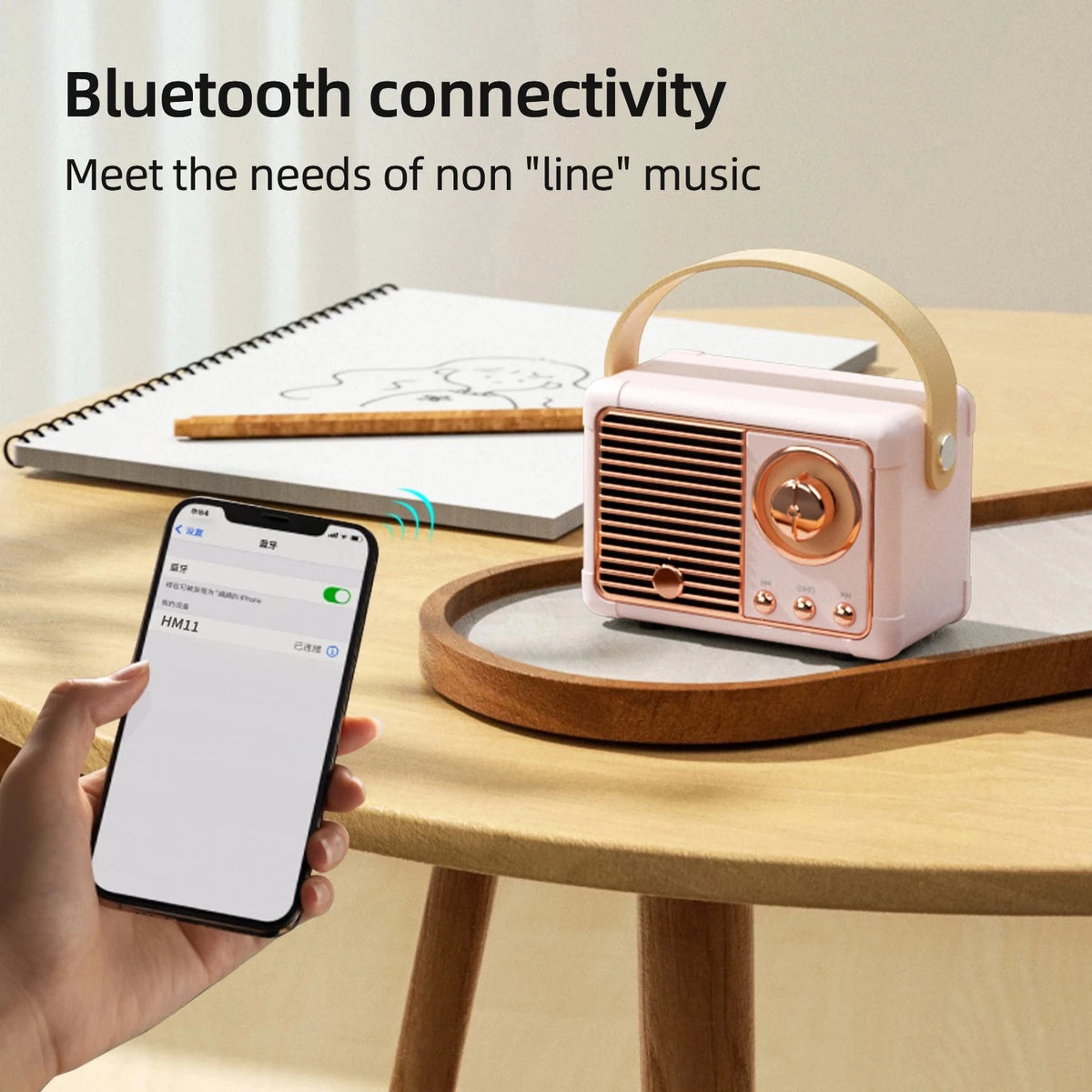 Pink vintage-style Bluetooth speaker on a wooden table with a smartphone connection.