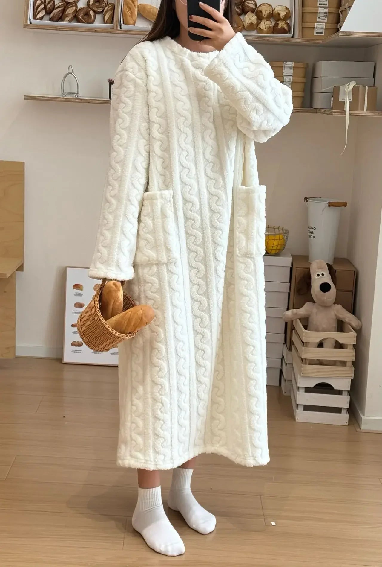 Person wearing a white cable knit robe in a room with wooden shelves and toys.