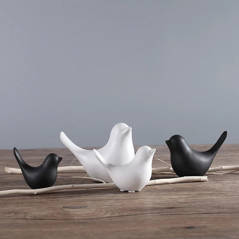Three ceramic birds in black, white, and gray on a wooden surface with a gray background