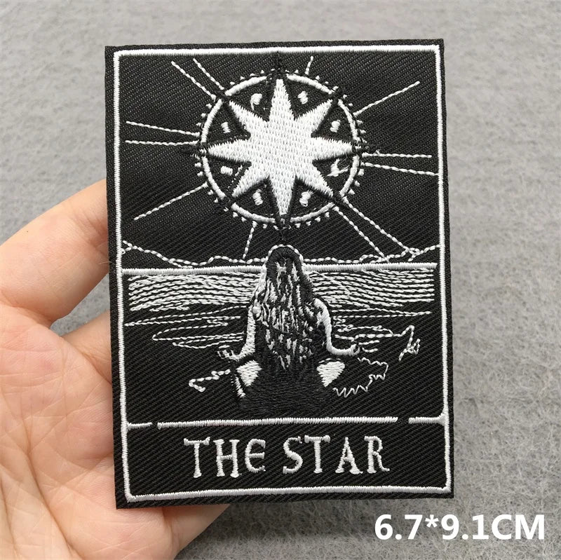 Embroidered patch with 'The Star' design held by a hand on a gray background