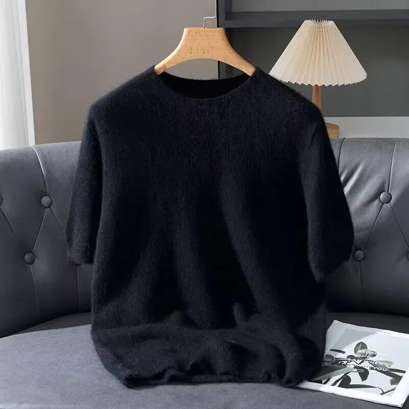 Black sweater on a hanger against a gray sofa with a lamp in the background