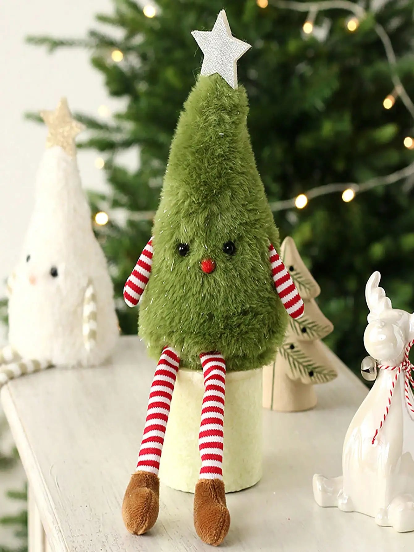 Plush Christmas tree toy with striped legs and a star on top, set against a festive background.