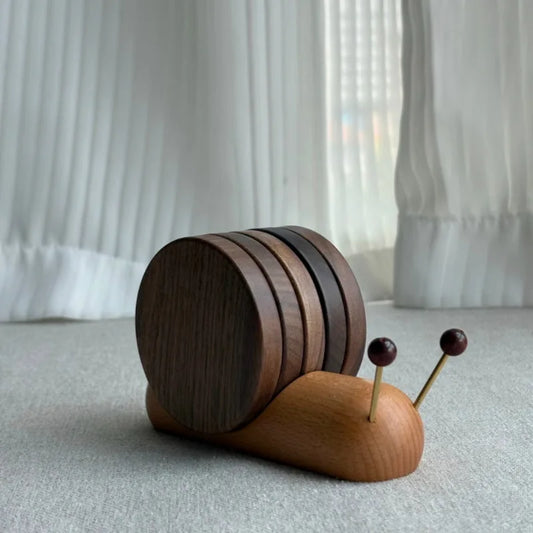 Wooden snail-shaped coaster holder with round wooden coasters forming its shell and two antennae topped with dark wooden beads.