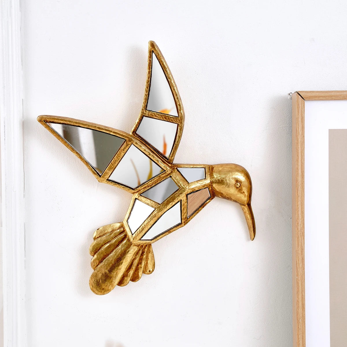 Gold hummingbird mirror on a white wall