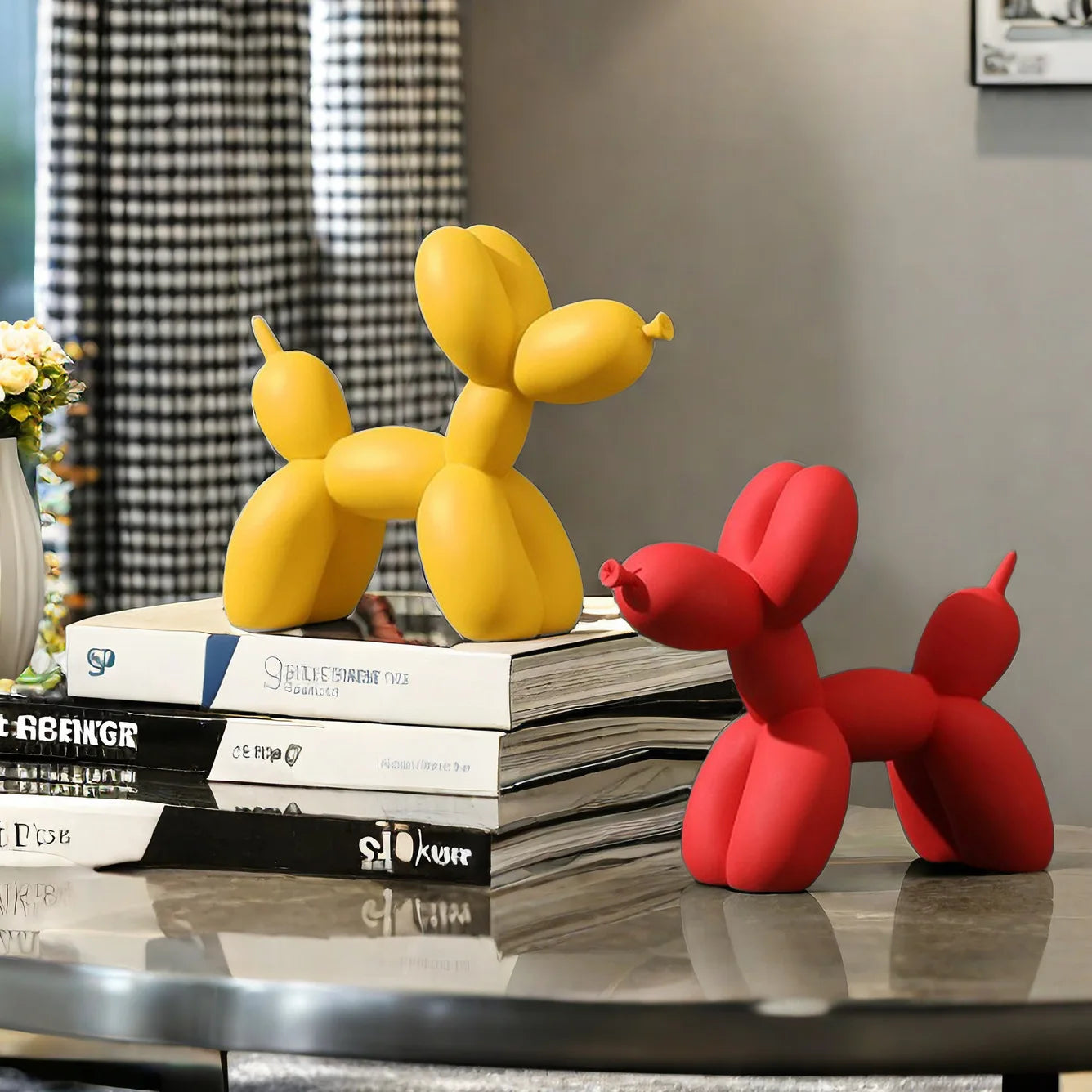Yellow and red balloon dog sculptures on a stack of books with a blurred background