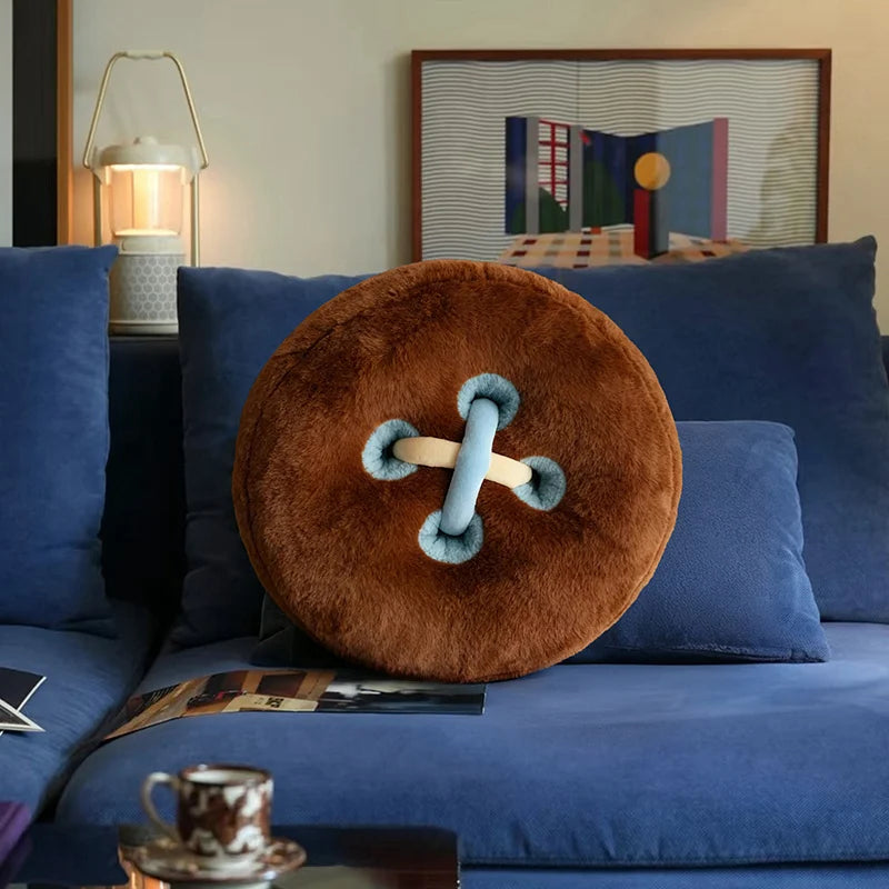 Brown round pillow with a blue and white design on a blue sofa in a living room.