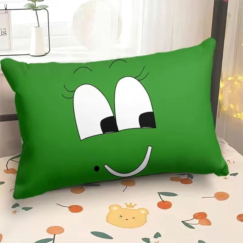 Green pillow with cartoon face design on a bed with a floral pattern