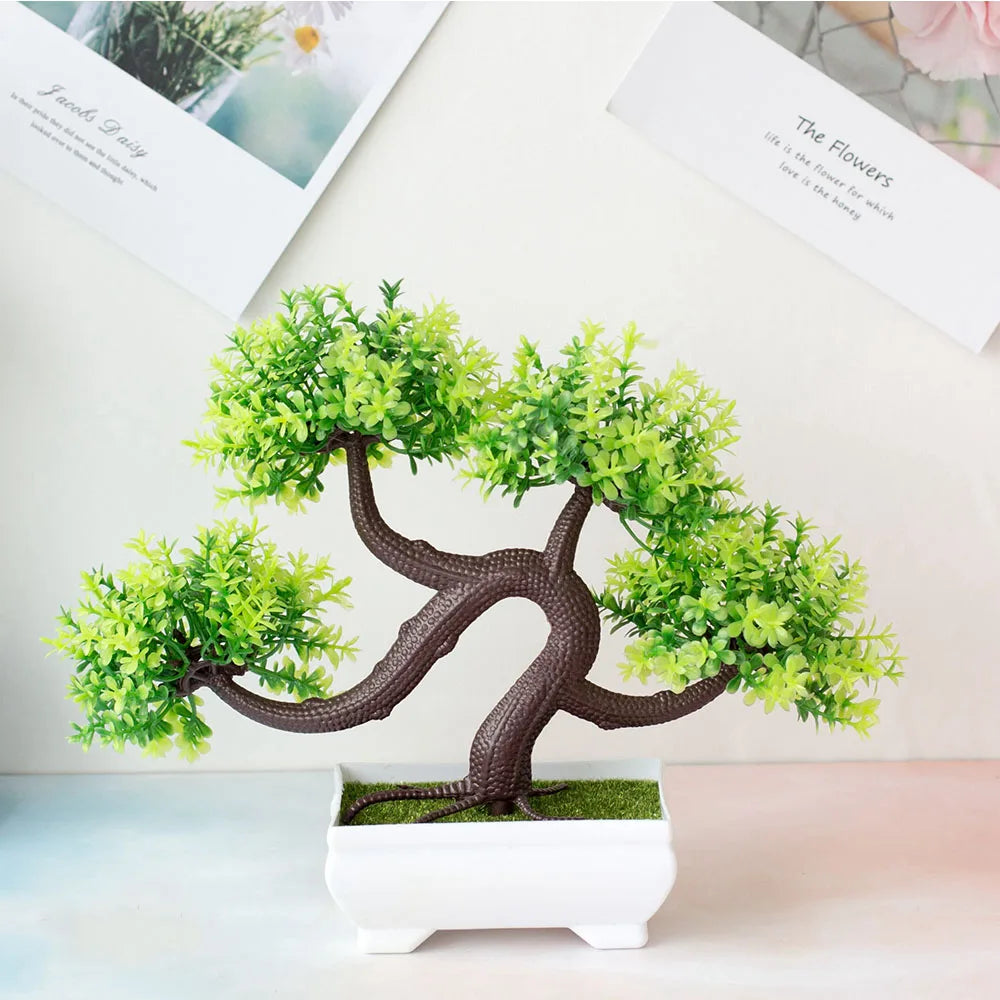 Artificial bonsai tree in a pot on a light surface with a magazine in the background