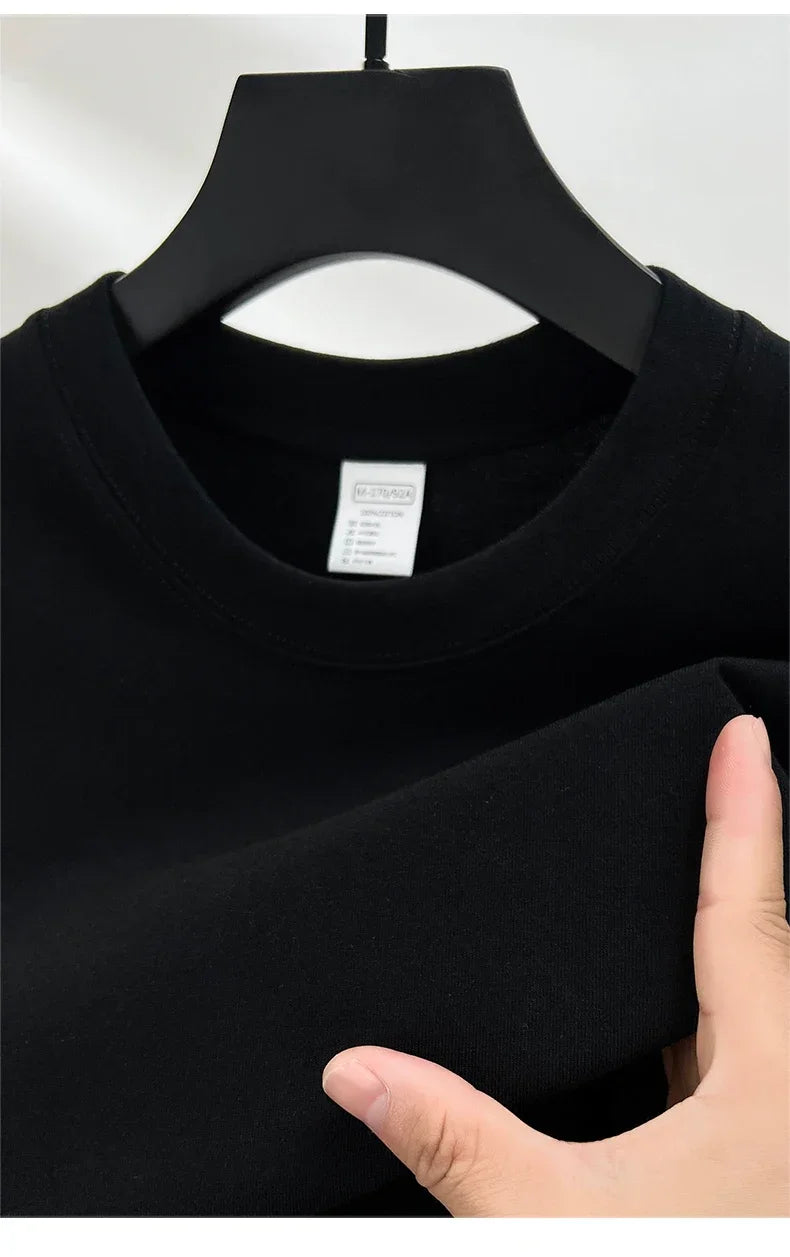 Black t-shirt on a hanger with a hand holding it, showing the collar and fabric texture.