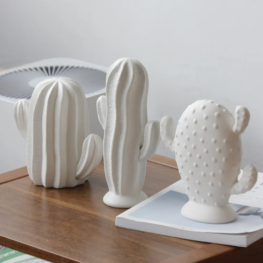 White ceramic cactus sculptures with matte finish displayed on a wooden table as modern minimalist home décor.