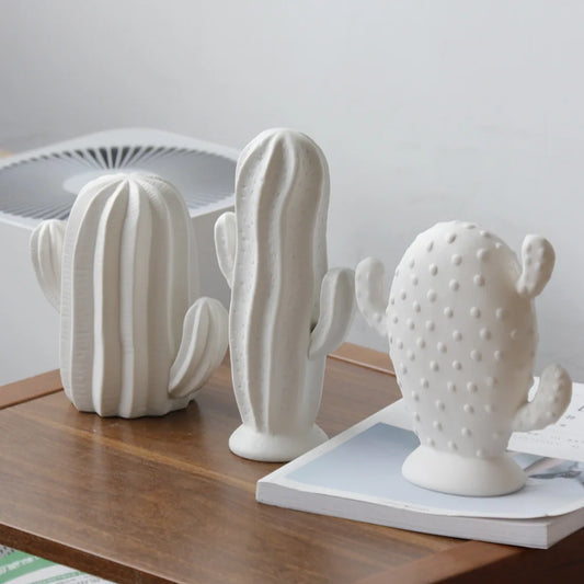 White ceramic cactus sculptures with matte finish displayed on a wooden table as modern minimalist home décor.