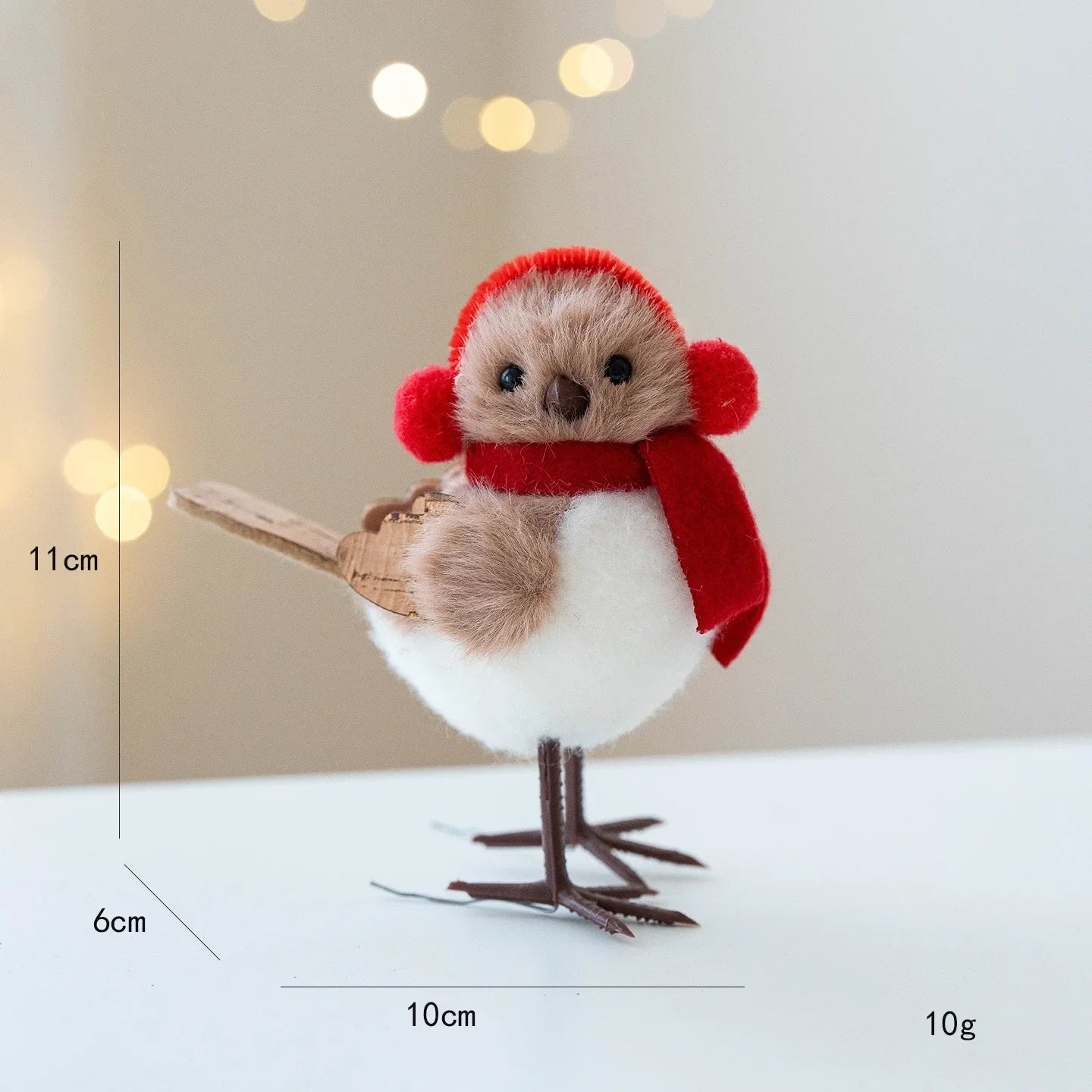 Small bird figurine with a red hat and scarf, standing on a white surface with a blurred light background.