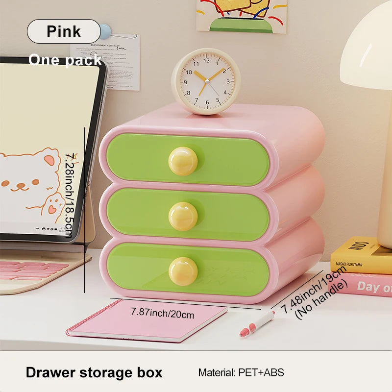 Pink and green drawer storage box on a desk with stationery items.