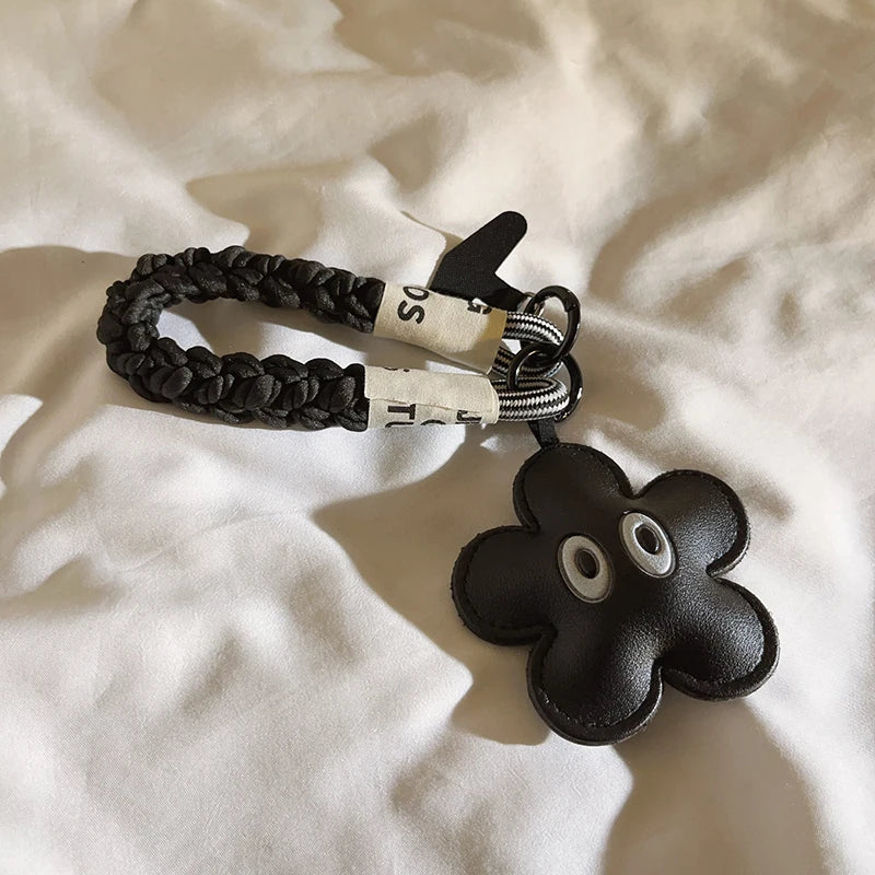 Black braided keychain with a flower-shaped key holder on a white fabric background