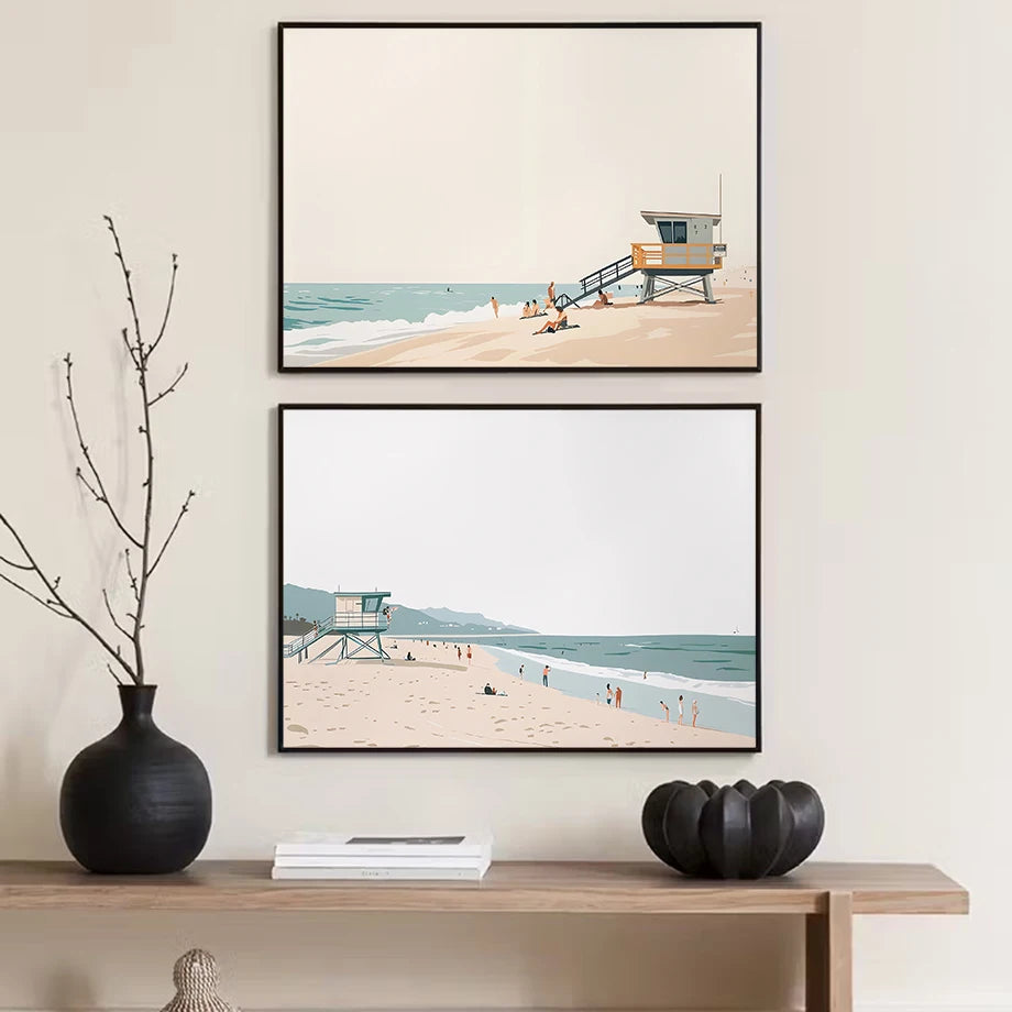 Two framed beach scene prints on a wall above a wooden console table with decorative items.