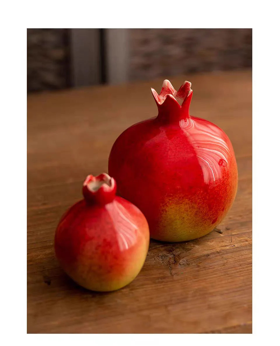 Two ceramic pomegranates on a wooden surface