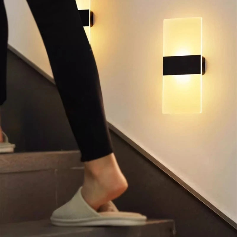Person wearing white slippers walking on a staircase with wall lights on.