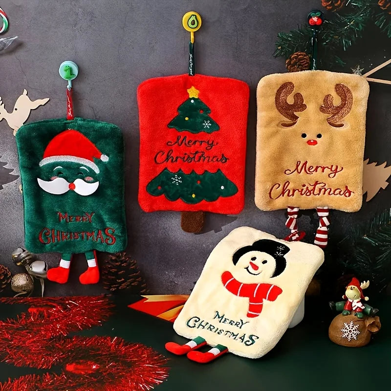 Four Christmas-themed plush hand towels hanging on a dark background with festive decorations.